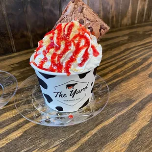 Strawberry ice cream topped with whip cream and a brownie