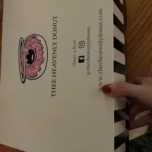 a hand holding a box of doughnuts