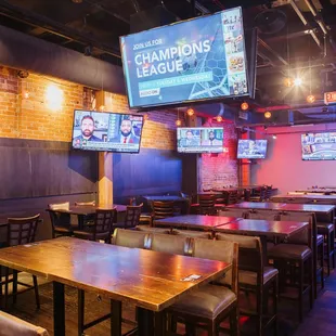 the inside of a sports bar with tables and televisions