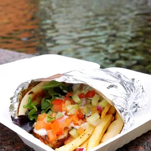 Roasted Pork Belly Gyro: tomato, onion, tzatziki sauce wrapped in warmed pita, pepperoncini and Greek pico ($13.75).