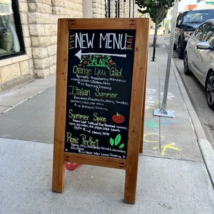 a menu board on a sidewalk