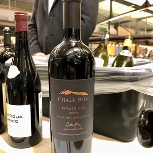 a man in a suit standing next to bottles of wine