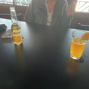 a woman sitting at a table with a bottle of beer