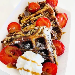 a plate of waffles with strawberries and whipped cream