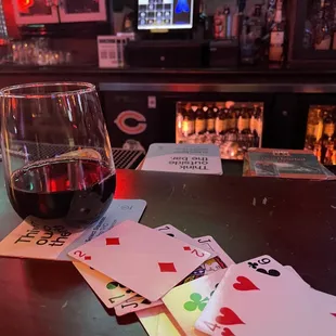 a glass of wine and playing cards