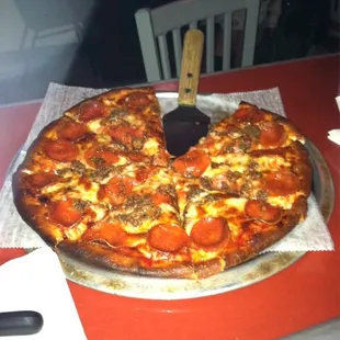 a pepperoni pizza with a spatula