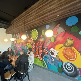 people sitting at a table in front of a colorful mural