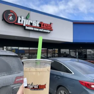 a hand holding a cup of iced coffee