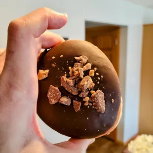 a hand holding a chocolate donut