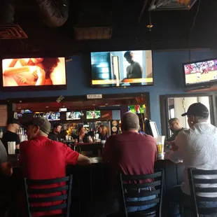 people sitting at a bar watching televisions