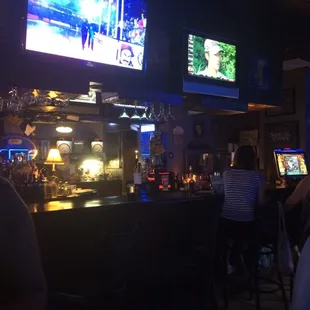people sitting at a bar watching tvs