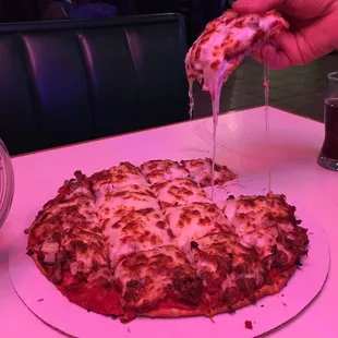 a person taking a slice of pizza