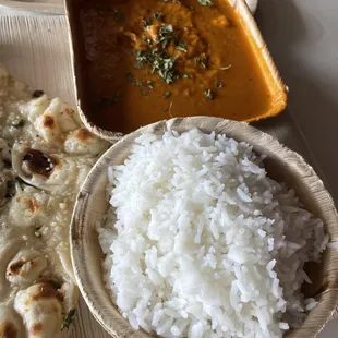 a bowl of rice, a bowl of curry, and a plate of naan
