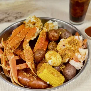 a bowl of crab legs, potatoes, corn, and potatoes