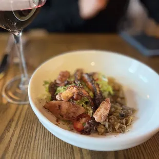 a bowl of food and a glass of wine