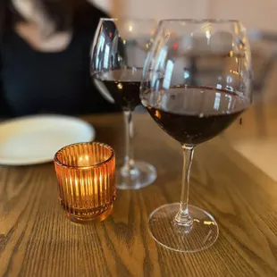 a woman sitting at a table with two glasses of wine