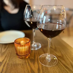 a woman sitting at a table with two glasses of wine