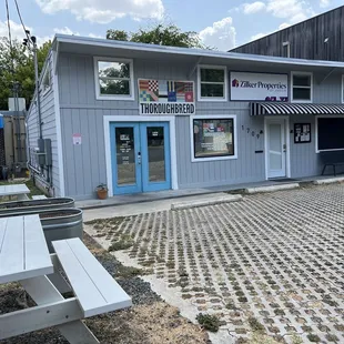 the front of a building with a picnic table outside