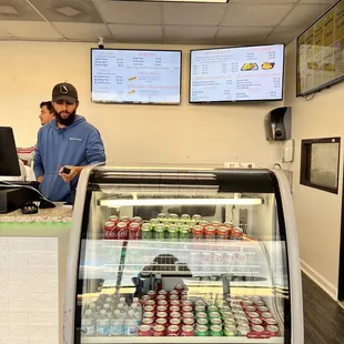 a man and a woman standing in front of a deli counter