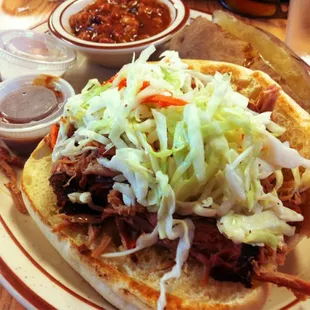 Slawburger Dinner: A pulled pork sandwich topped with slaw and served with baked beans and a baked potato and side salad.