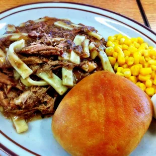 The Beef &amp; Noodles Special (half-order) served over mashed potatoes with a side of corn and a roll.
