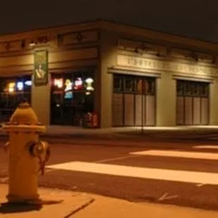 a yellow fire hydrant on the corner of a street