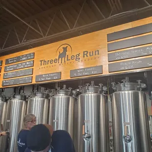 a man and a woman standing in front of a row of beer kegs