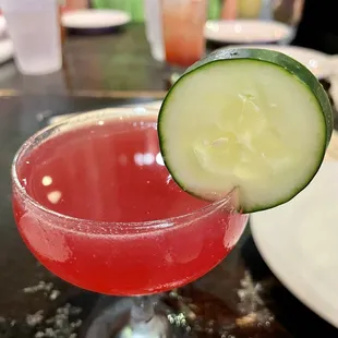 a cocktail with a cucumber on the rim