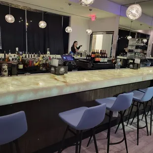 a bar with blue chairs and a marble counter