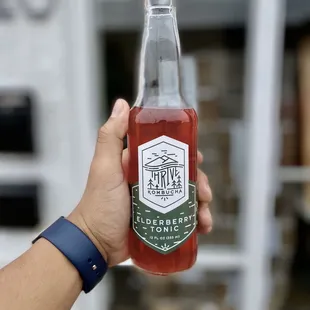 a hand holding a bottle of kombucha