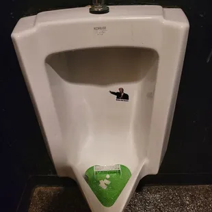 a white urinal with a green sticker