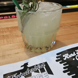 a cocktail with a rosemary sprig in a glass