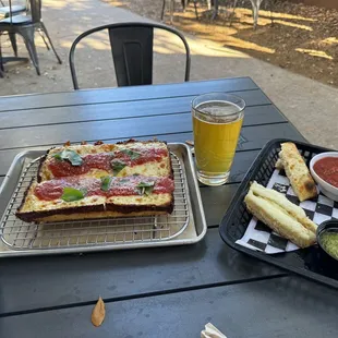 Cheese pizza, beer and half eaten cheeses bread