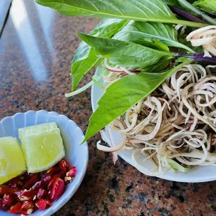 Garnishes include: bean sprouts, water spinach, banana flower, mint, Thai basil