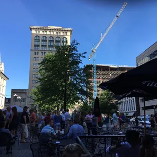 a crowd of people sitting at tables in a city square