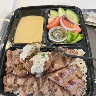 a tray of meat, rice, and vegetables