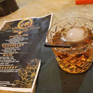 a glass of whiskey and a menu