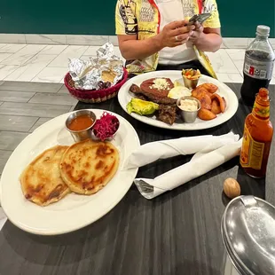 a woman sitting at a table with plates of food