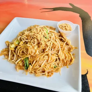 a plate of noodles with a side of dipping sauce