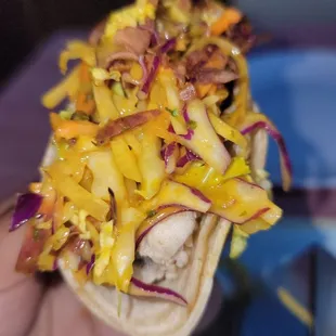  a person holding a taco with shredded cheese