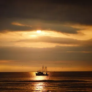 a boat in the ocean at sunset