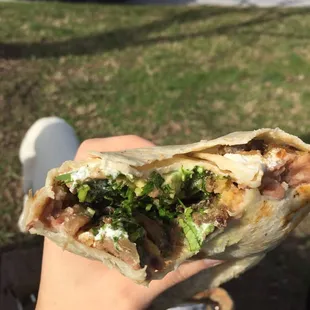 Carne asada burrito filled with all kinds of yummy. Refried beans, rice, avocado, sour cream, onions, cilantro, Carne Asada.