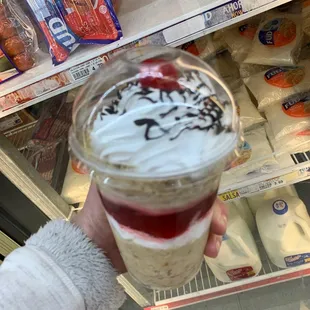 a hand holding a cup of yogurt