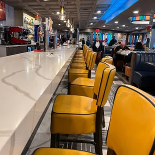 a row of yellow chairs in a diner