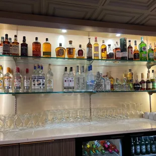 a shelf of liquor bottles and glasses