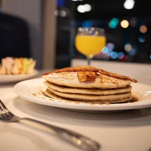 a plate of pancakes and a glass of orange juice