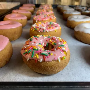 a row of doughnuts with pink frosting and sprinkles