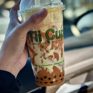 a hand holding a cup of iced coffee