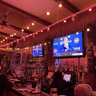 people sitting at a bar watching tv