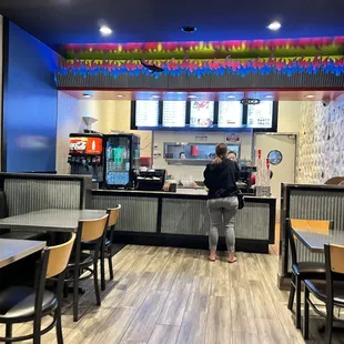 a woman standing at a counter in a fast food restaurant